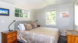 A bedroom with a bed, two windows, a nightstand, a lamp, and a dresser. - Copper John, close to the Ski Fields here in the McKenzie. Quiet and private. (Middle Valley)