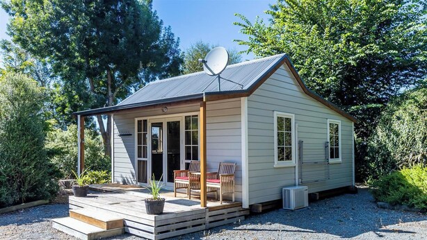 A small, single-story cabin with a covered porch, a satellite dish, and a gravel driveway. - Copper John, close to the Ski Fields here in the McKenzie. Quiet and private. (Middle Valley)