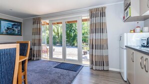 A modern kitchen with a built-in microwave, a sink, and a countertop. There is a dining area with a table and chairs, and a large window with curtains. - Copper John, close to the Ski Fields here in the McKenzie. Quiet and private. (Middle Valley)