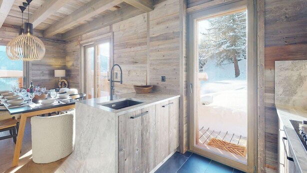 Eine moderne Küche mit Holzwänden, einem großen Fenster und Blick auf eine verschneite Landschaft.