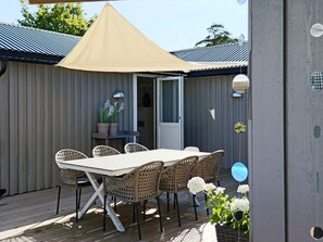 An outdoor patio with a table and chairs, a beige canopy, and potted plants. - 4 Star Holiday Home in Mellbystrand (Mellbystrand)
