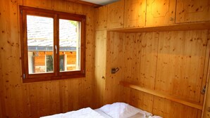 A wooden room with a bed, a window, and a door. - Cozy Apartment With Rhone Valley View (Nendaz)