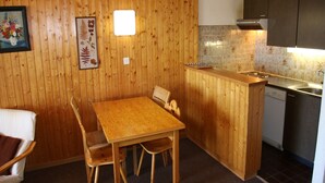 Eine gemütliche Küchenzeile mit Holzwänden, einem Esstisch mit Stühlen, einer kleinen Spüle und einem Geschirrspüler.