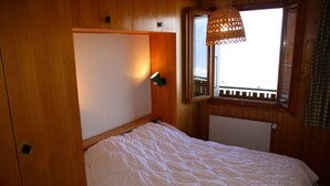 Ein Einzelbett in einem Zimmer mit Holzwänden und einem Fenster mit Aussicht.