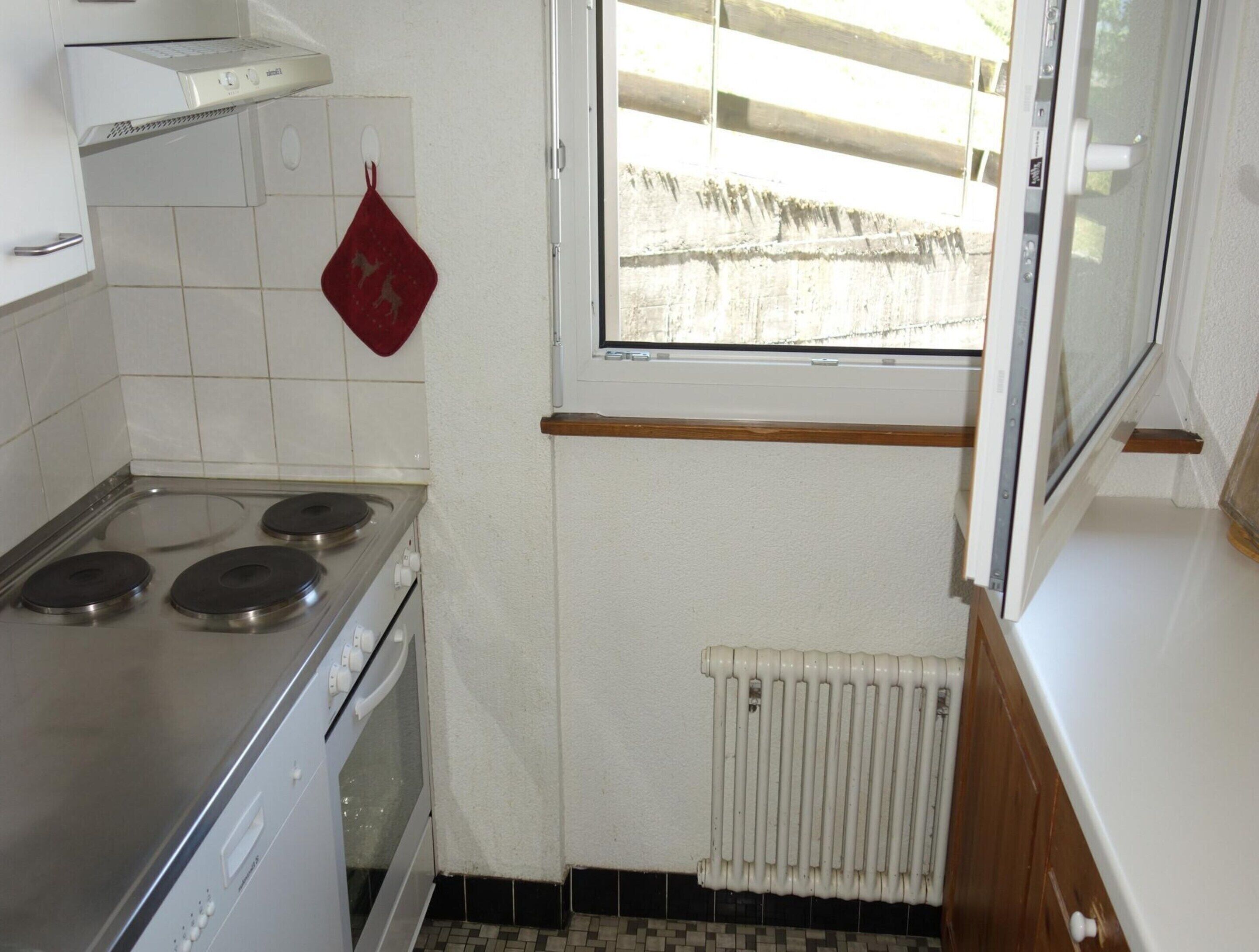 A compact kitchen with a stove, oven, and a window overlooking a balcony.