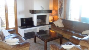 Ein Wohnzimmer mit Kamin, Fernseher und Ledersofas.