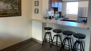 Eine moderne Küche mit einer Arbeitsplatte, Barhocker und gerahmten Bildern an der Wand.