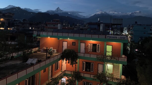 A building named Pokhara Lodge with a balcony, a view of the mountains, and a well-lit exterior. - New Pokhara Lodge, Lakeside (Pokhara)