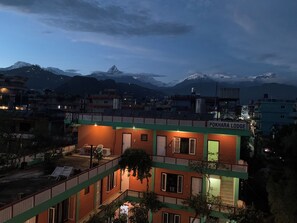 A building named Pokhara Lodge with a balcony, a view of the mountains, and a well-lit exterior. - New Pokhara Lodge, Lakeside (Pokhara)
