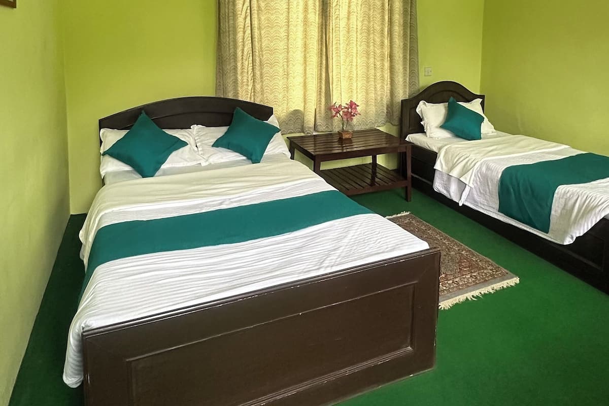 Quarto com duas camas, ventilador de teto e janela com cortinas.
