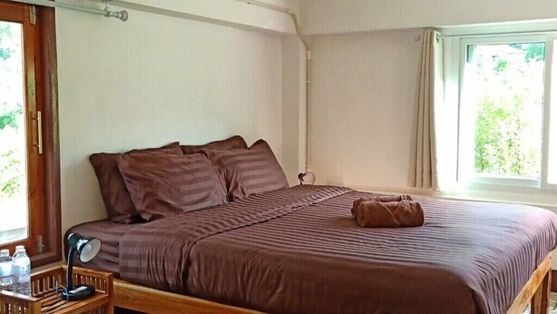 A single bed with a wooden frame and a patterned floor, a small bedside table with a lamp, and a window with curtains. - GJ TOUR
Cozy homestay in beautiful Pangmapha, Tham Lot with AC. (Pang mapha,)