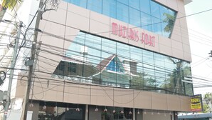Un edificio con una grande facciata vetrata e la scritta "MUZIKIS HOTEL" sulla facciata.