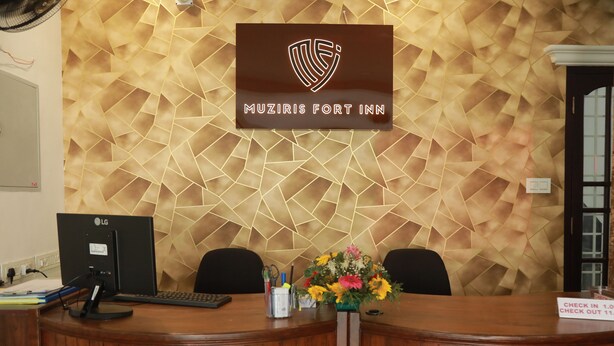 Una reception con il logo aziendale, un computer e un vaso di fiori.