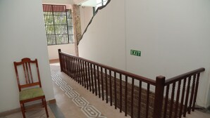 Una scala con ringhiera in legno, una sedia e un segnale di uscita sul muro.