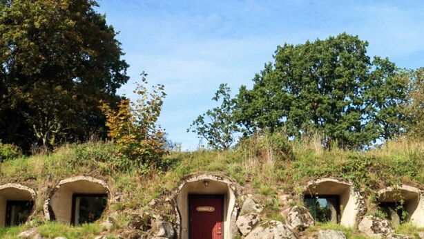 A rustic stone structure with a red door, surrounded by rocks and trees. - Scenic Holiday Home in Hoor (Hoor)