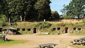 A campsite with picnic tables, a small shelter, and several stone structures. - Scenic Holiday Home in Hoor (Hoor)