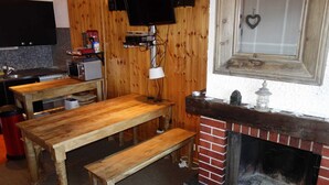 A rustic interior with a wooden table, bench, and brick fireplace. - Trendy Apartment in the Heart of Hills (Sion)