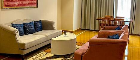 A living room with a sofa, a loveseat, a coffee table, and a patterned rug.