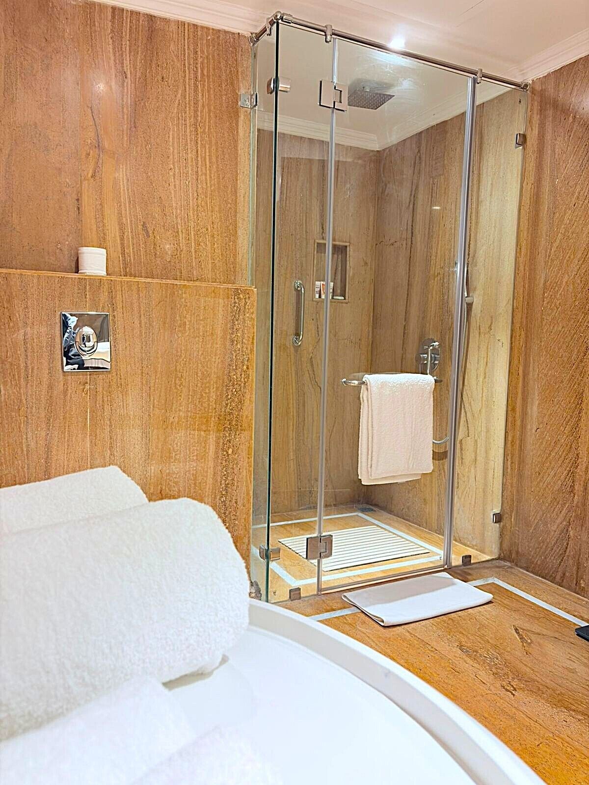 Une salle de bain moderne avec une douche à parois de verre, un meuble-lavabo en bois et une baignoire blanche.