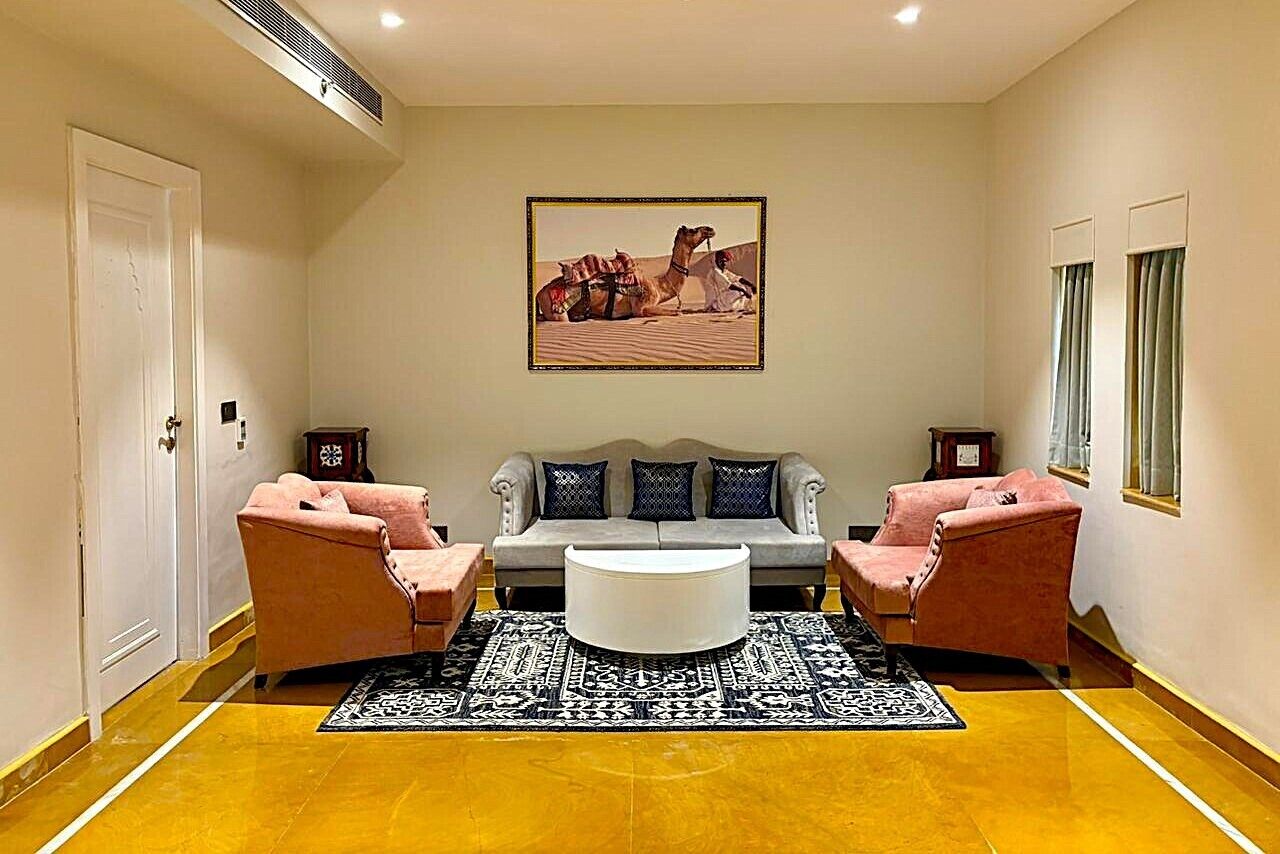 A living room with a sofa, two armchairs, a coffee table, and a patterned rug.
