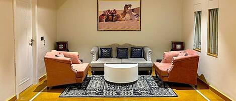 A living room with a sofa, two armchairs, a coffee table, and a patterned rug.