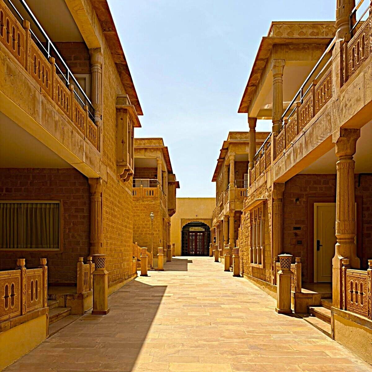 A corridor with traditional architecture, featuring a central door and symmetrical balconies.