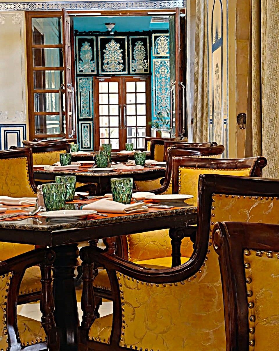 A traditional dining area with wooden tables and yellow upholstered chairs.