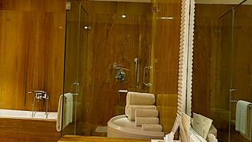 Un baño moderno con ducha envuelta en vidrio, tocador de madera y un espejo grande.