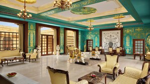 Una habitación lujosa con candelabros ornamentados, asientos mullidos y elaborados diseños en las paredes.