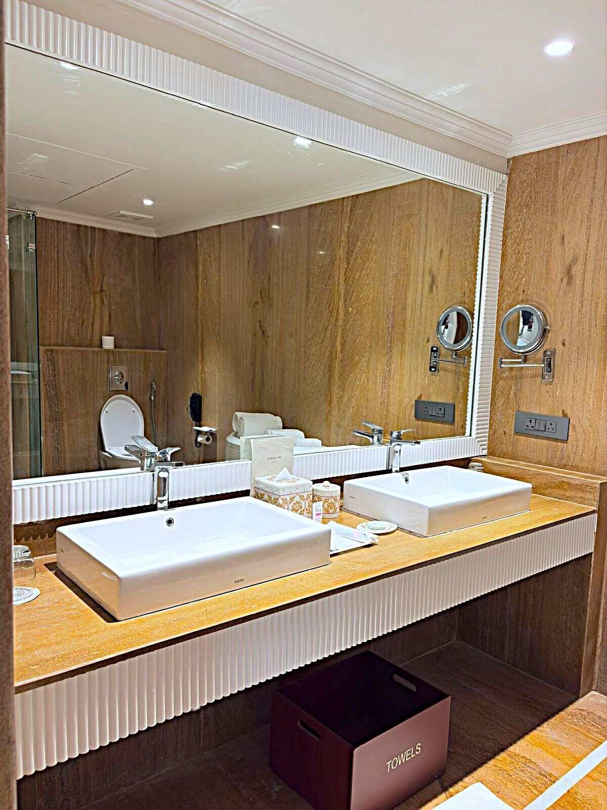 A modern bathroom with two sinks, a large mirror, and a towel rack.