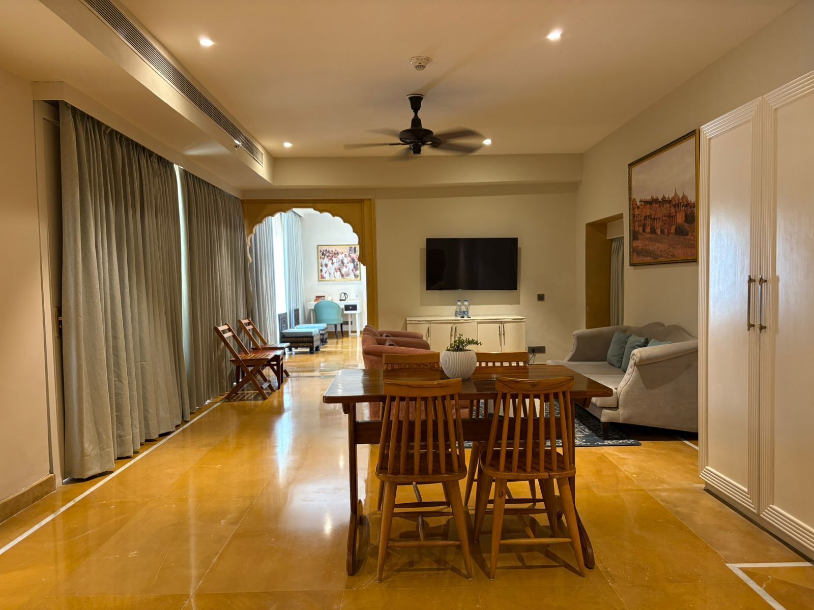 Amplia sala de estar con mesa de comedor, sofás, televisor y ventilador de techo.