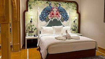 A hotel room with a large bed, a decorative headboard, two bedside lamps, and a nightstand.