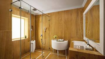 Un baño moderno con pared de madera, cabina de ducha de vidrio, lavamanos blanco y un espejo grande.