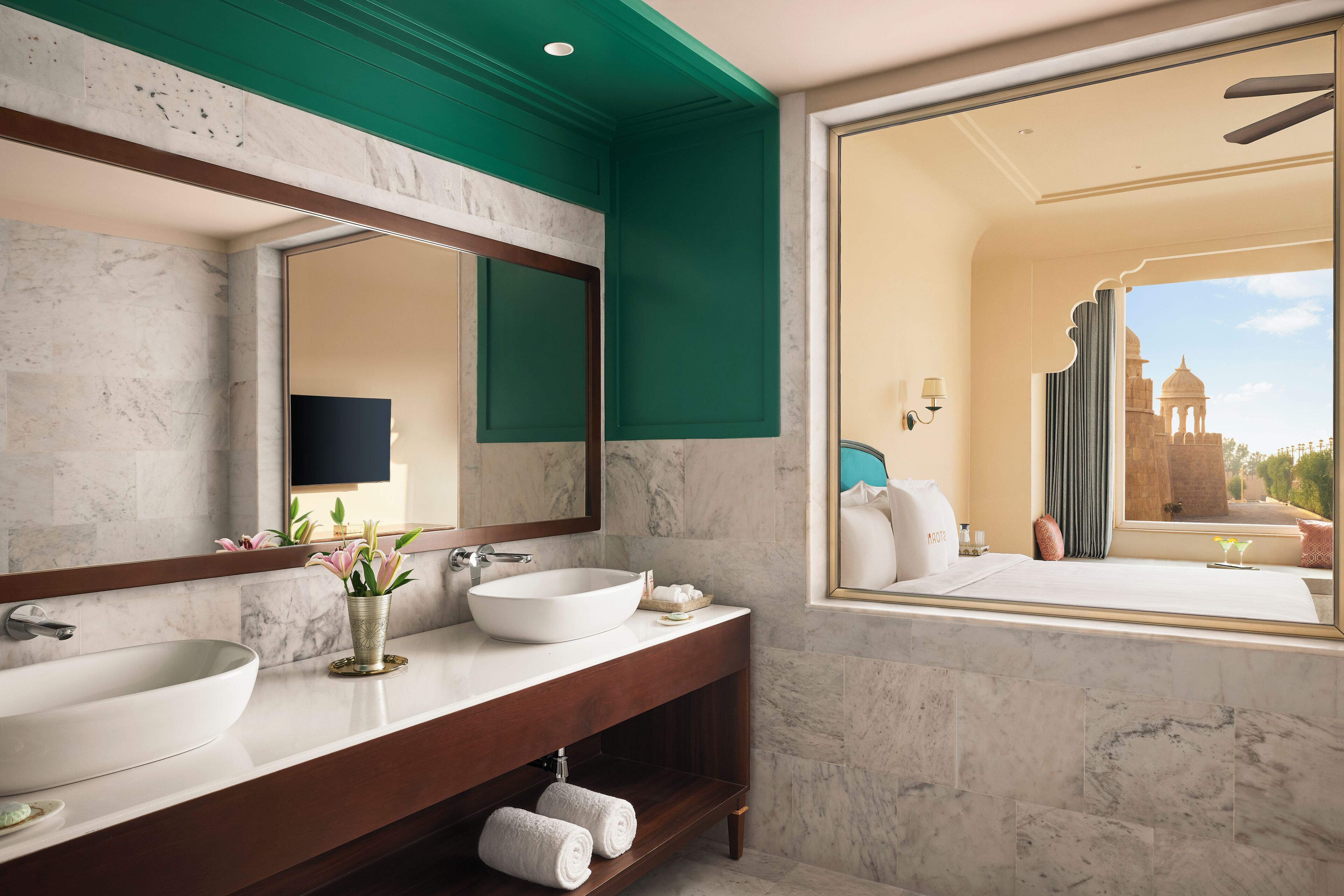 A bathroom with two sinks, a large mirror, and a view of a historic building through a window.