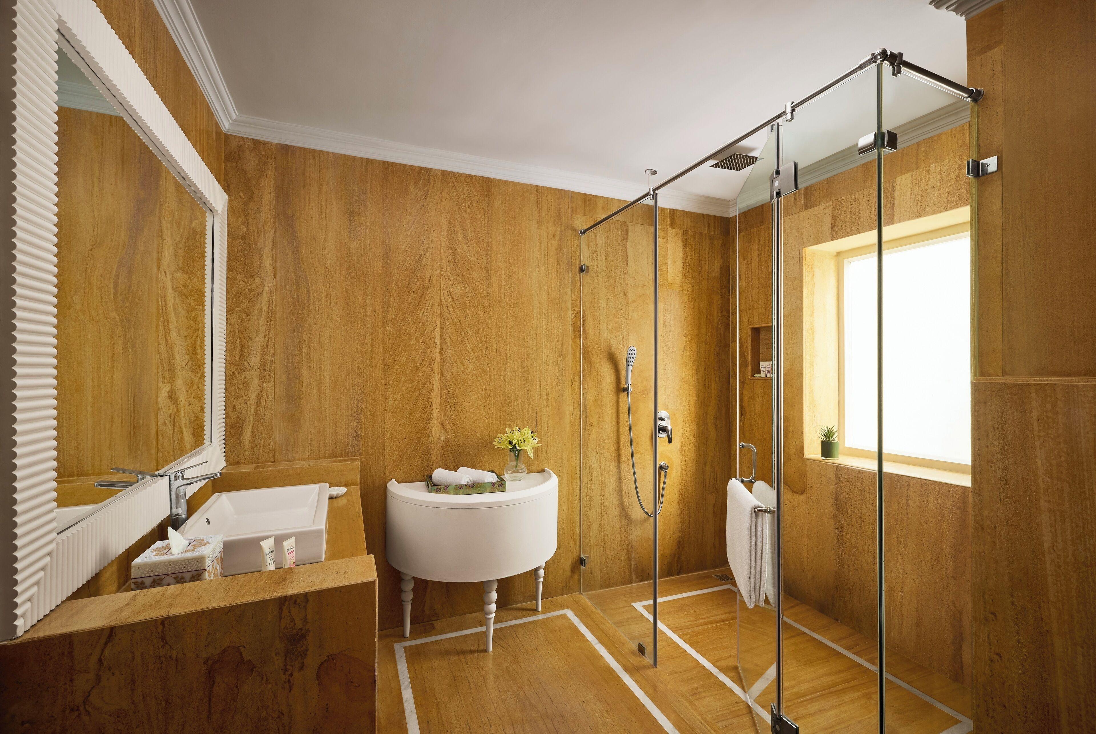 A bathroom with a wooden wall, a white sink, a mirror, and a shower area.