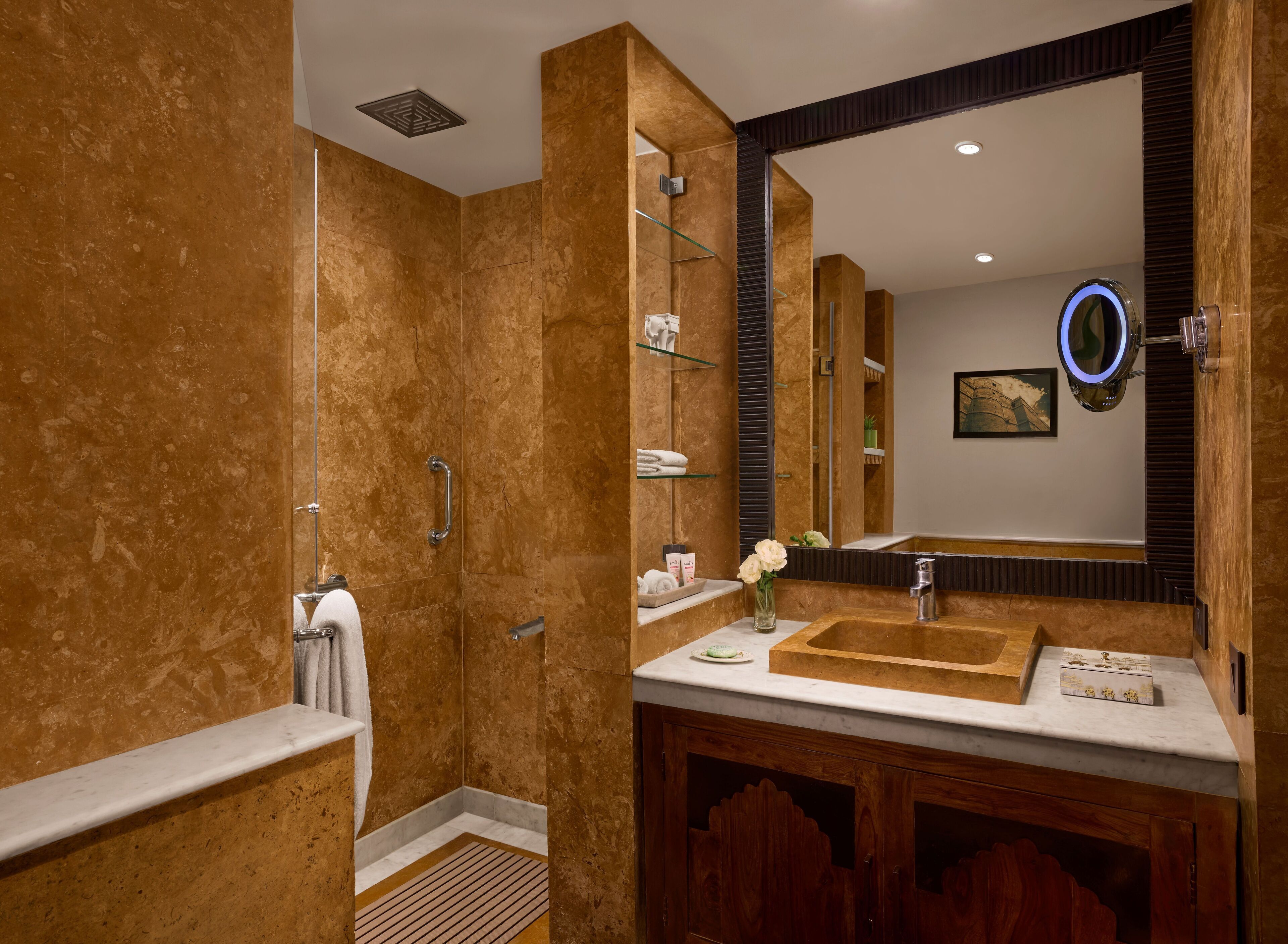 Un baño moderno con cabina de ducha, tocador con espejo grande y armario de madera.