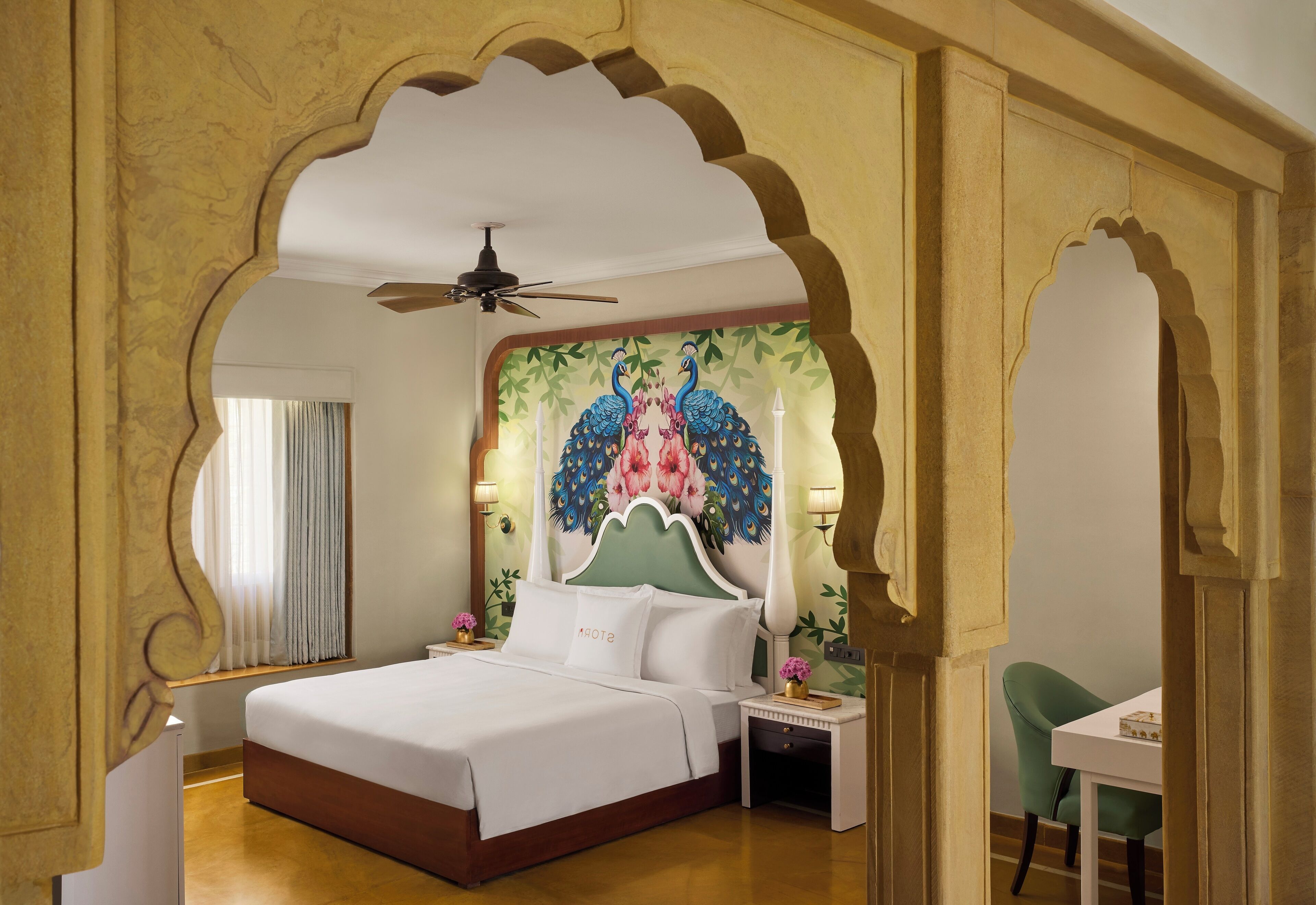 A hotel room with a large bed, a nightstand, a chair, and a decorative wall mural.