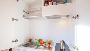 A compact kitchenette with a sink, a stove, and a small countertop. - Mountain Views In Camedo (Centovalli)