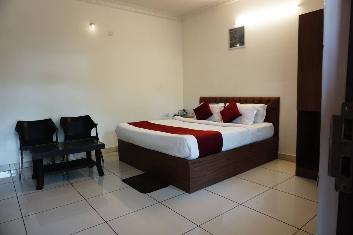 A bedroom with a large bed, two chairs, a small table, and a nightstand.