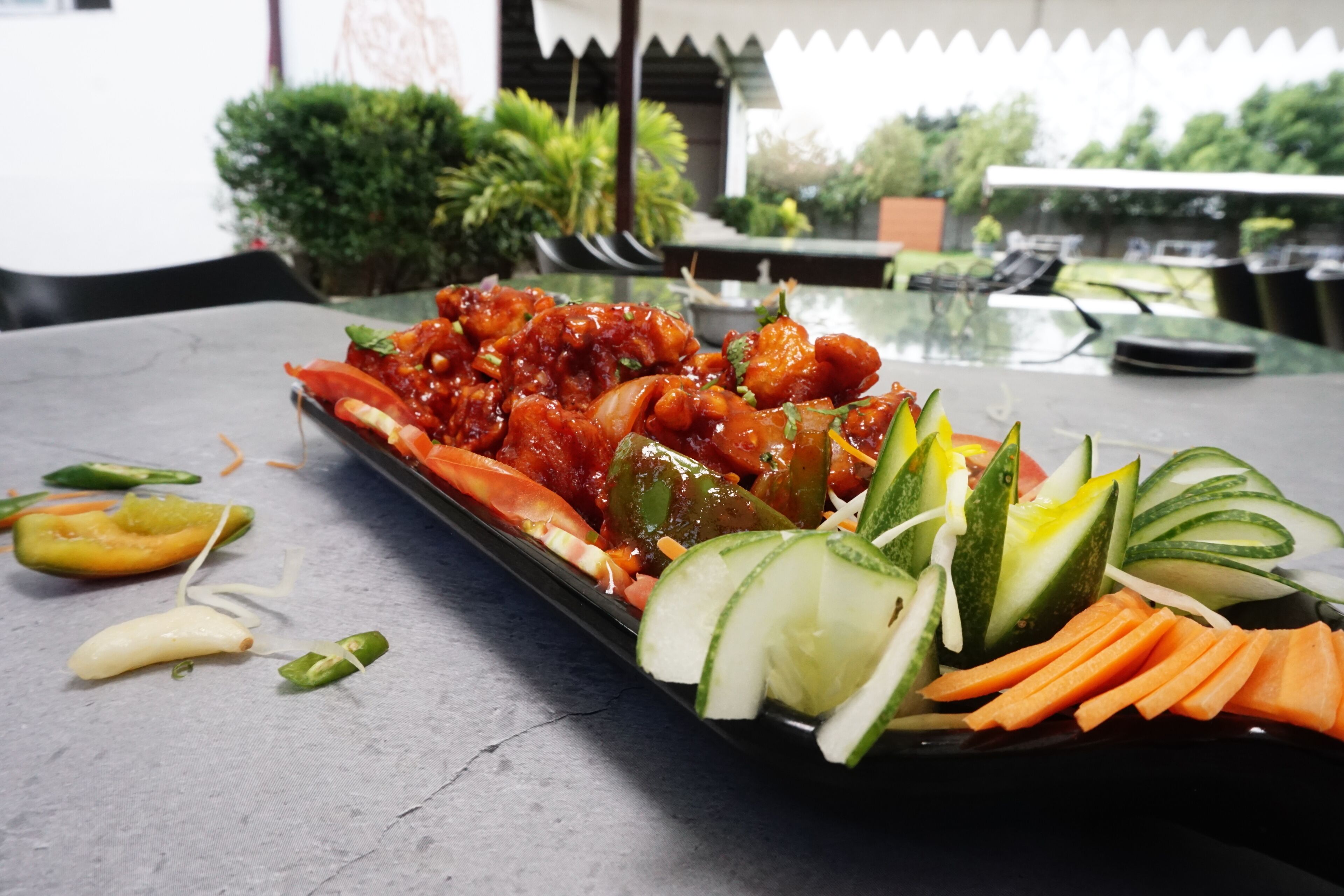 Une table avec une assiette de nourriture, comprenant des légumes et un plat nappé d’une sauce rouge.