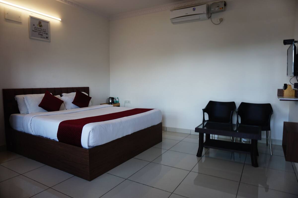 A hotel room with a bed, bedside table, and two chairs.