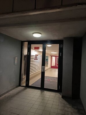 A hallway with a tiled floor leading to a room with a red door.