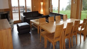 A wooden interior with a dining area, sofas, and a fireplace. - Apartment With Panoramic Views (Veysonnaz)