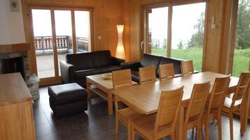 A wooden interior with a dining area, sofas, and a fireplace.