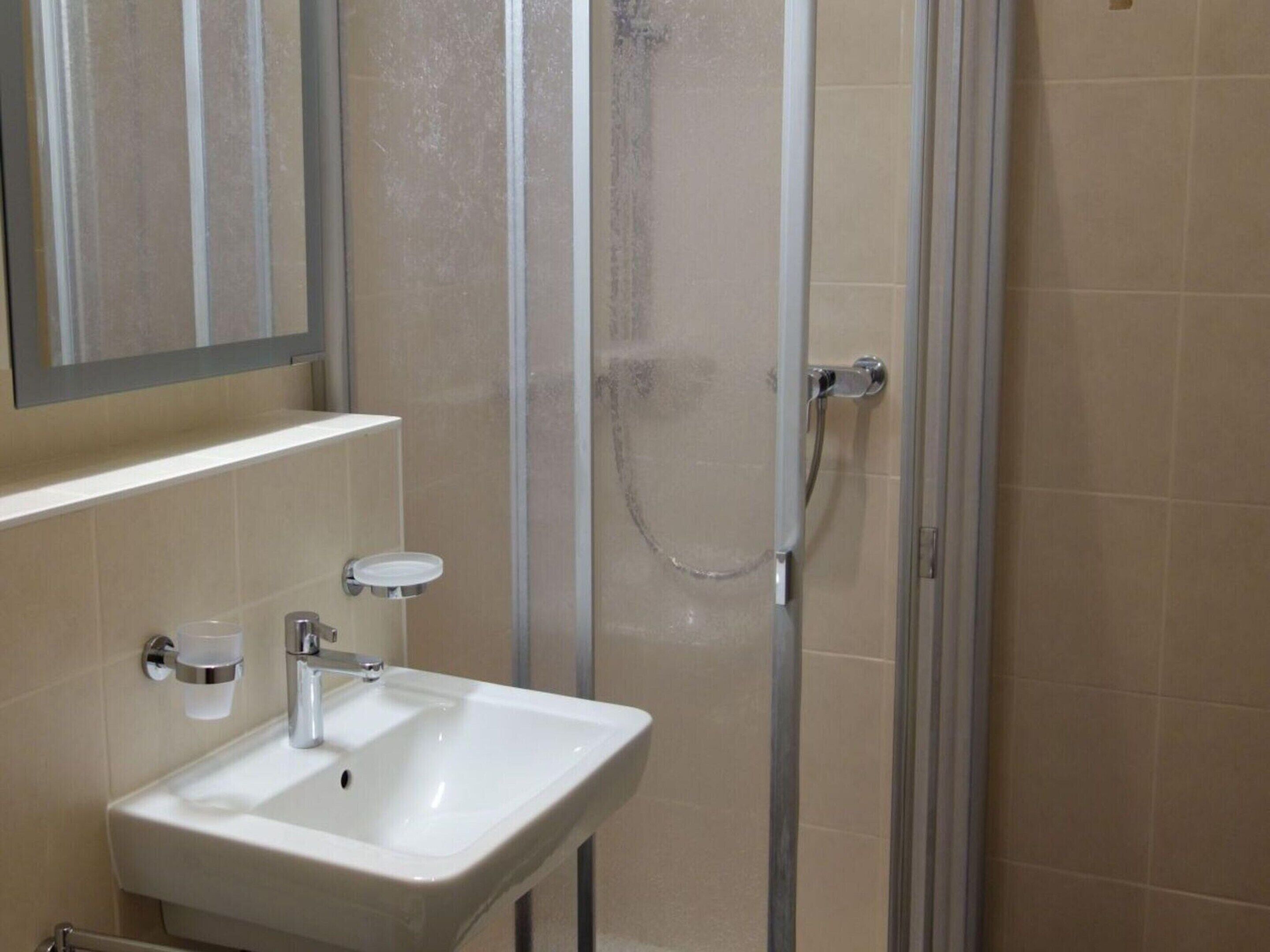 A bathroom with a white sink, a mirror, and a glass shower enclosure.