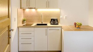 Una cucina compatta con mobili bianchi, un lavandino, un tostapane e una piccola pianta in vaso.