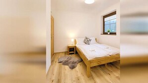 Una camera da letto accogliente e intima con un letto singolo, un comodino, una lampada, una finestra e un pavimento in legno.