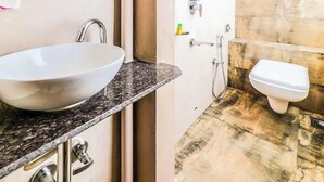 A bathroom with a white sink, a toilet, and a shower area. - Glitz Hotels Aksha International (Mumbai)