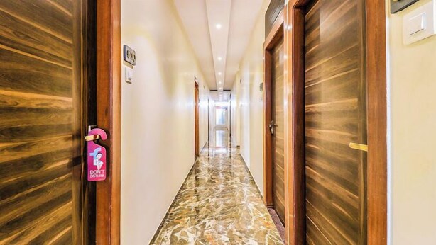 A hallway with wooden doors and a marble floor. - Glitz Hotels Aksha International (Mumbai)