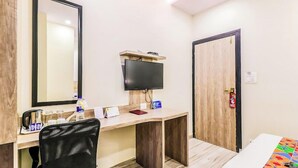A hotel room with a desk, chair, TV, and a bed. - Glitz Hotels Aksha International (Mumbai)